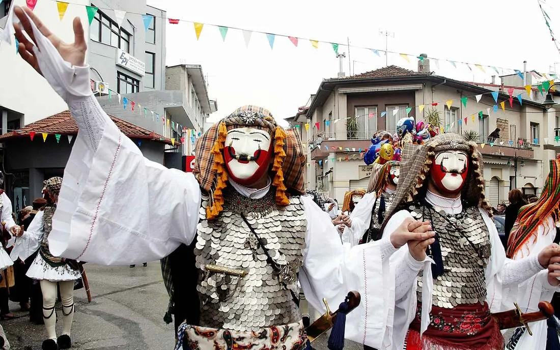 Traditional Naoussa carnival masked figures wearing elaborate coin-covered costumes and distinctive red and white masks