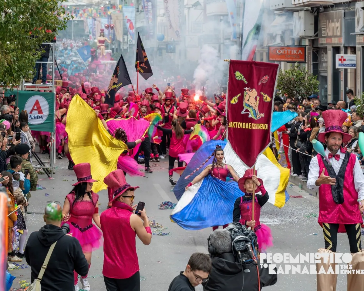 Colorful Rethymno Carnival parade in Crete with costumed performers, flags, and confetti