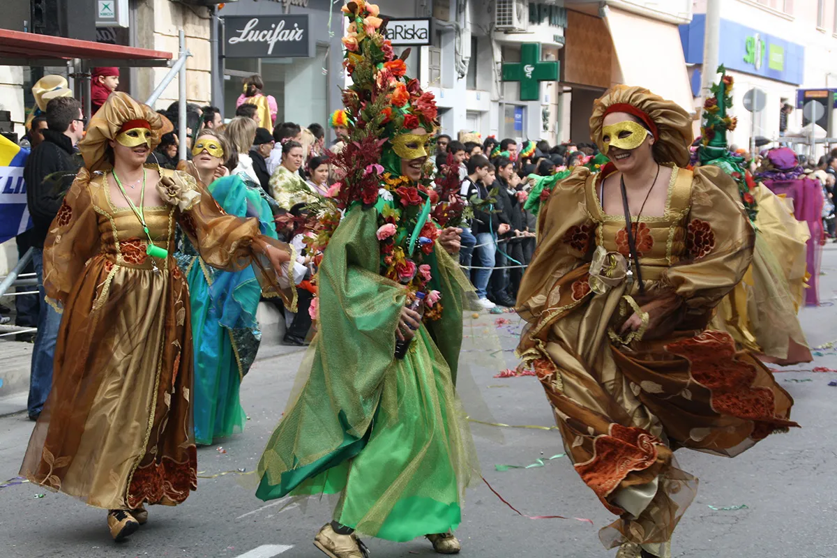 Costumed carnival revelers in golden Venetian-style masks and gowns during Patra Carnival parade